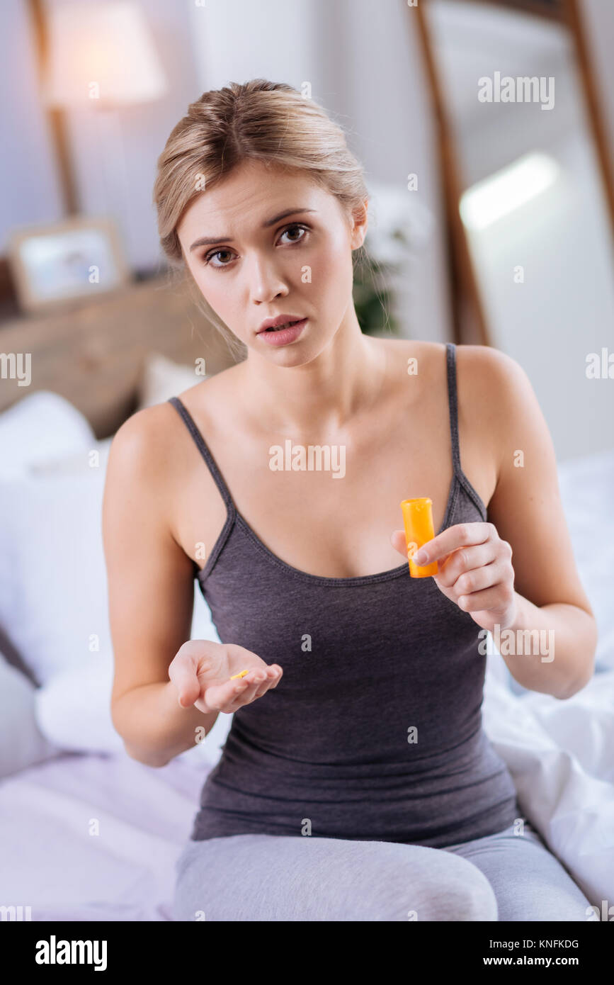 Worried woman holding plusieurs capsules sur sa main Banque D'Images
