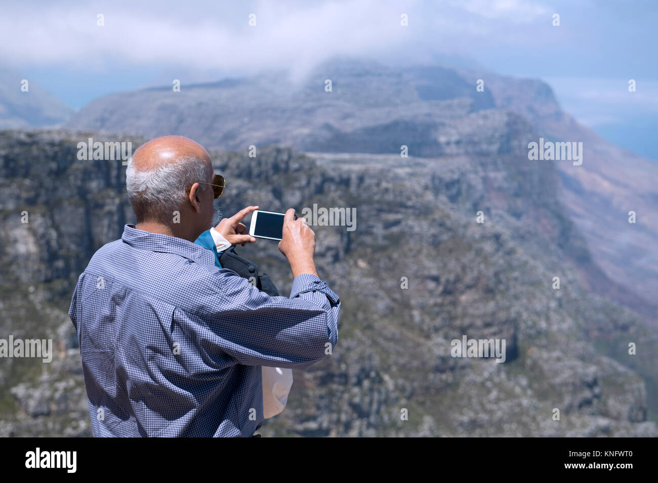 Tourist en utilisant un téléphone mobile pour prendre une photo de la vue depuis le sommet de la Montagne de la table au Cap, Afrique du Sud Banque D'Images