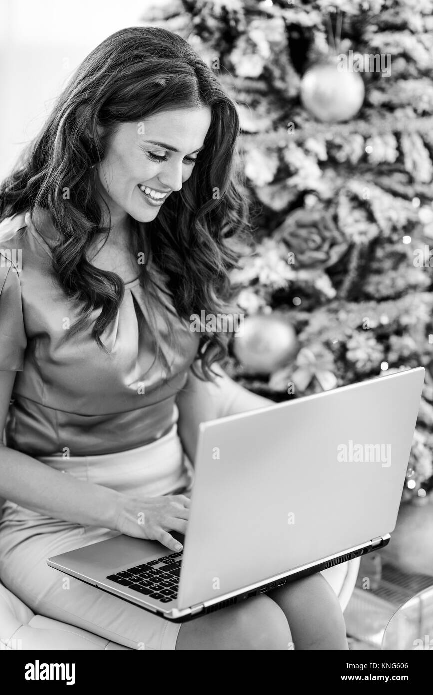 Happy young woman using laptop near Christmas Tree Banque D'Images