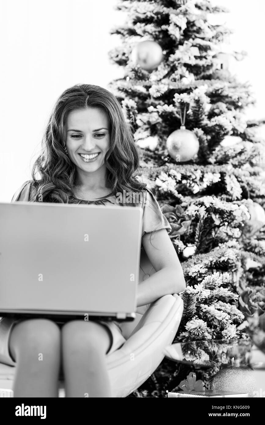 Happy young woman using laptop near Christmas Tree Banque D'Images