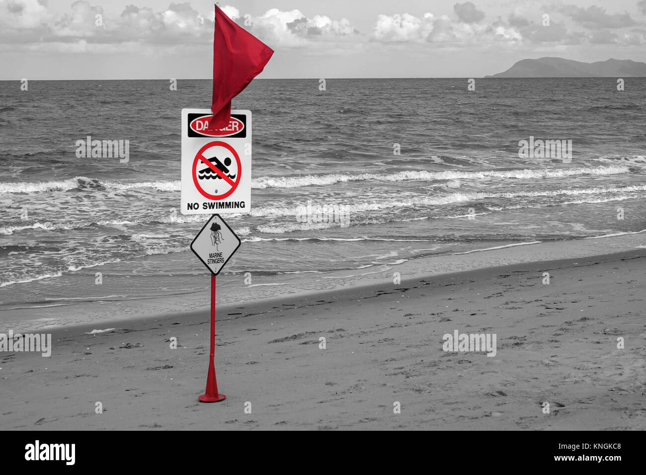 Drapeau d'avertissement rouge sur plage avec piscine aucun danger sign et de méduses image. Couleur en surbrillance gris mât contre paysage costal tropical Banque D'Images