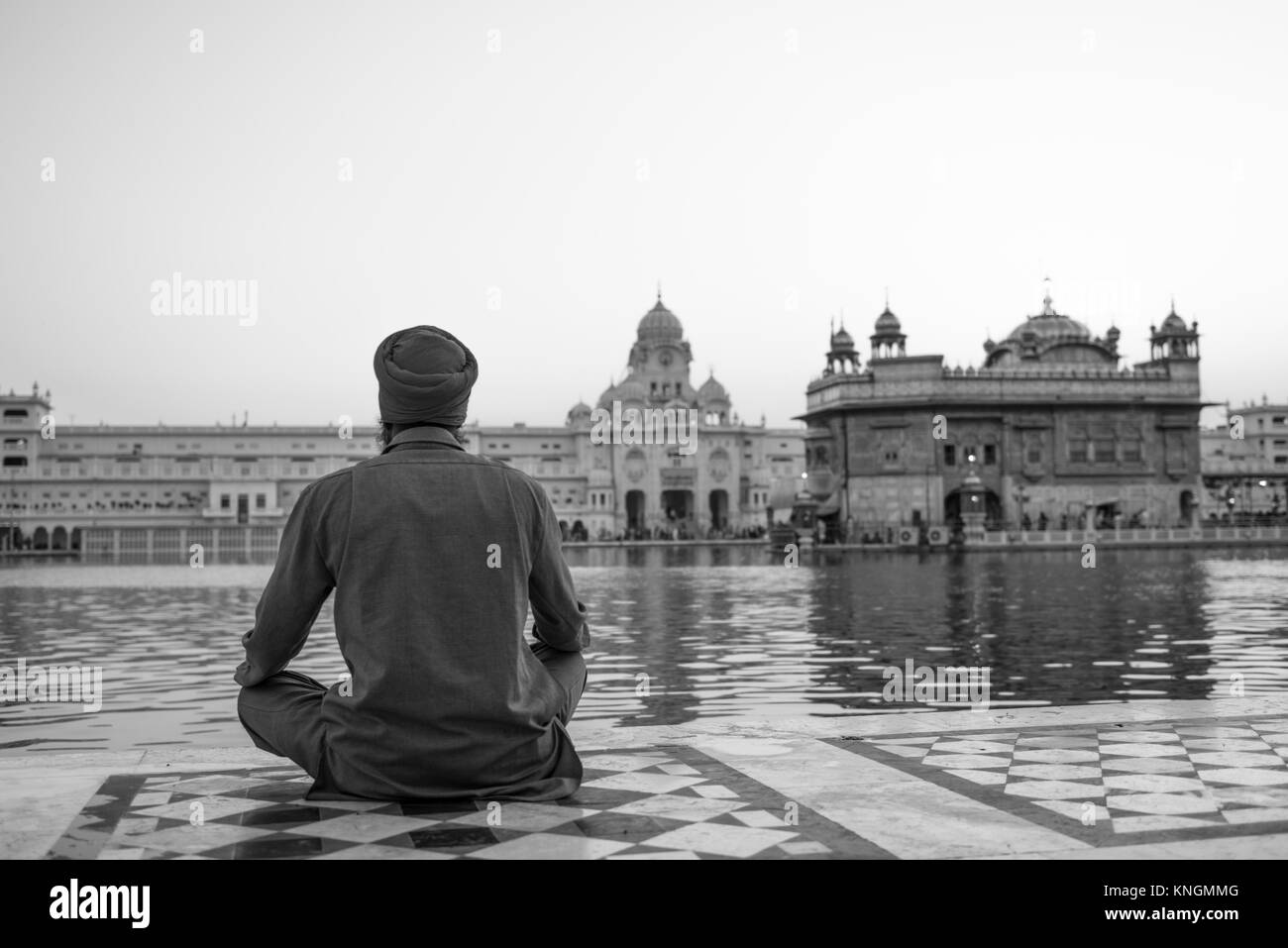 Photo noir et blanc de l'arrière de l'homme Indien priant devant le lac sacré à Sri Harmandir Sahib, connu sous le nom de Temple d'or, site du sikhisme, l Banque D'Images