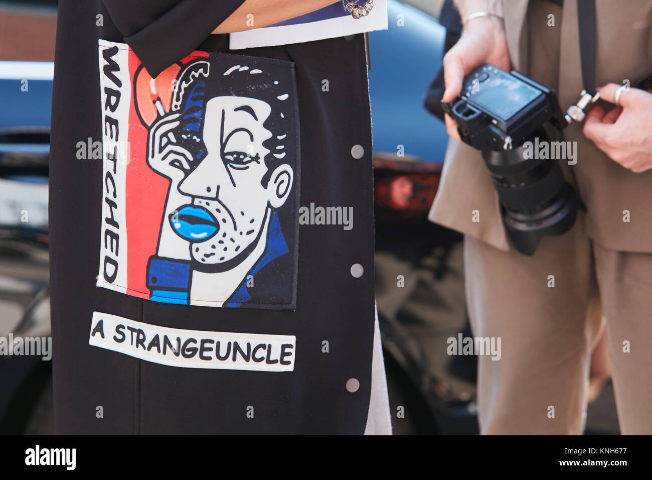MILAN - 24 SEPTEMBRE : Femme avec manteau noir avec l'homme face avec les lèvres bleues avant design fashion show Trussardi, Milan Fashion Week street style sur sept. Banque D'Images