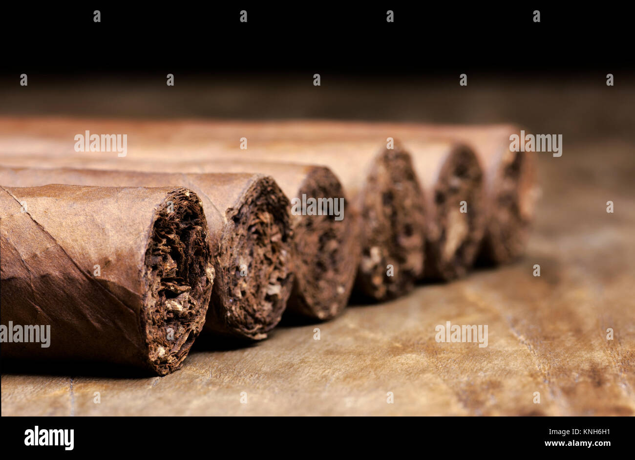Rangée de six cigares cubains allongé sur une vieille table en bois avec un arrière-plan flou Banque D'Images