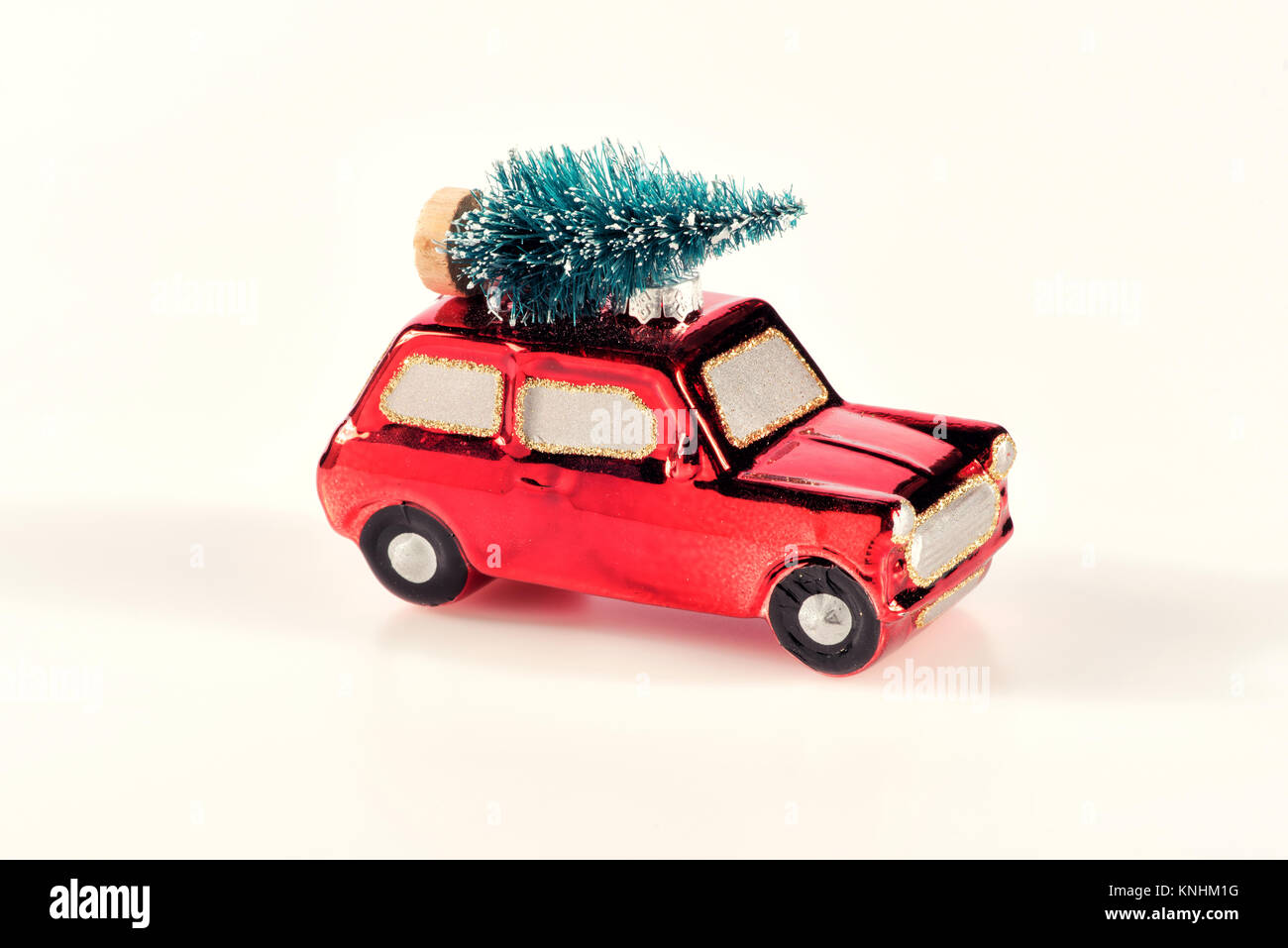 Petite voiture jouet rouge vif avec l'arbre de Noël en équilibre sur le toit d'un concept de vacances festives sur un fond blanc Banque D'Images Petite voiture jouet rouge vif avec l'arbre de Noël en équilibre sur le toit d'un concept de vacances festives sur un fond blanc Banque D'Images