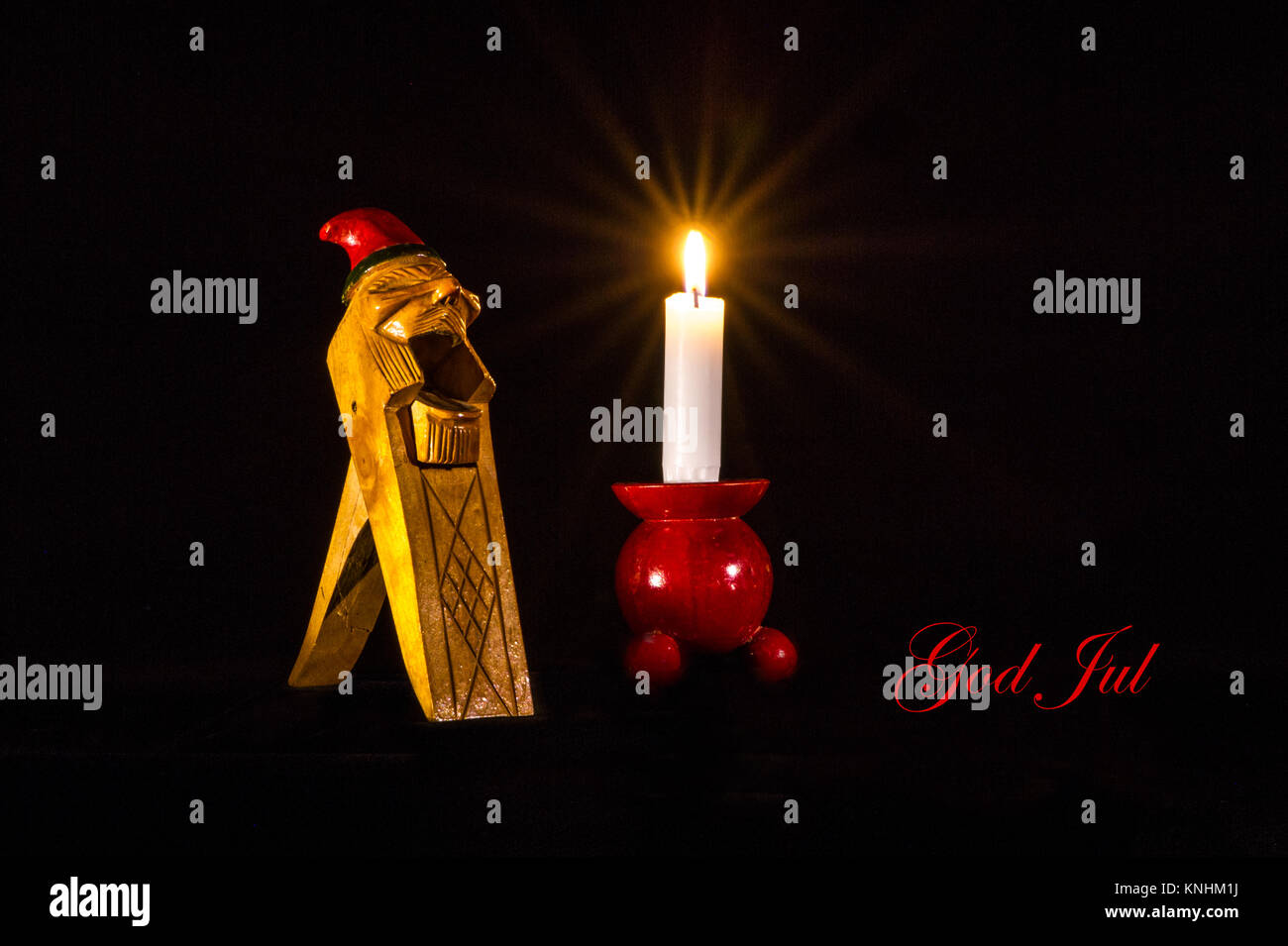 Voeux de Noël en suédois sur un gnome norvégienne en bois Collectible Handcarved Nut Cracker, accompagnée d'une bougie sur un chandelier de bois rouge typique. Banque D'Images
