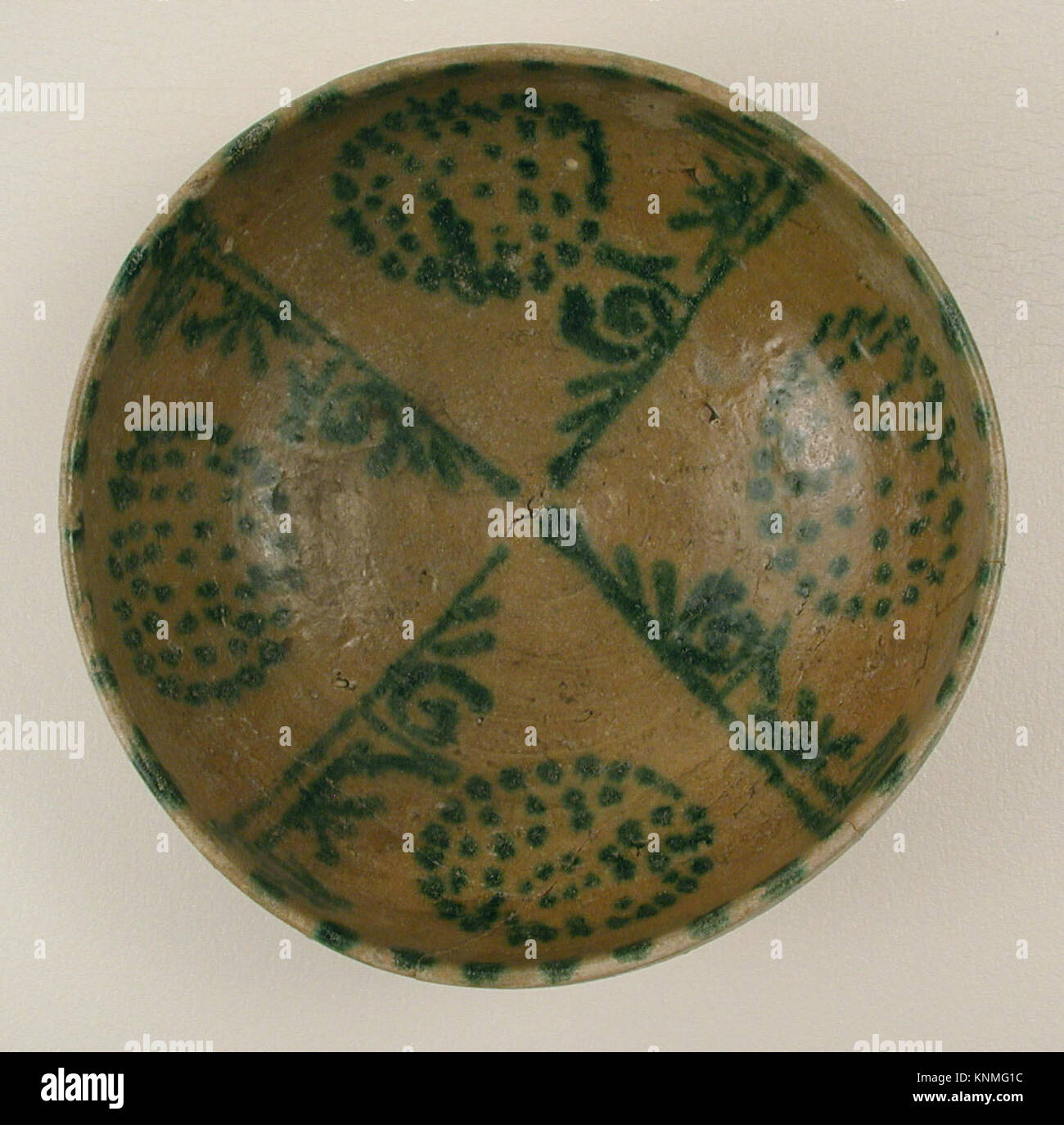 Un bol en faïence des IXe et Xe siècles de Nishapur, Iran, avec des pseudo-inscriptions vertes et des amas de taches sur une barbotine jaune sous glaçage transparent. Banque D'Images