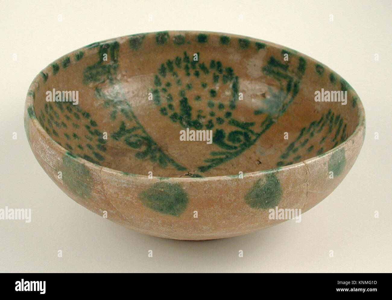 Un bol en faïence des IXe et Xe siècles de Nishapur, Iran, avec des glissades jaunes, des pseudo-inscriptions vertes et des amas de taches sous une glaçure transparente. Banque D'Images