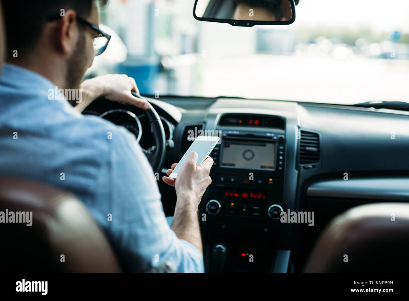 L'homme à l'aide de téléphone en conduisant la voiture Banque D'Images