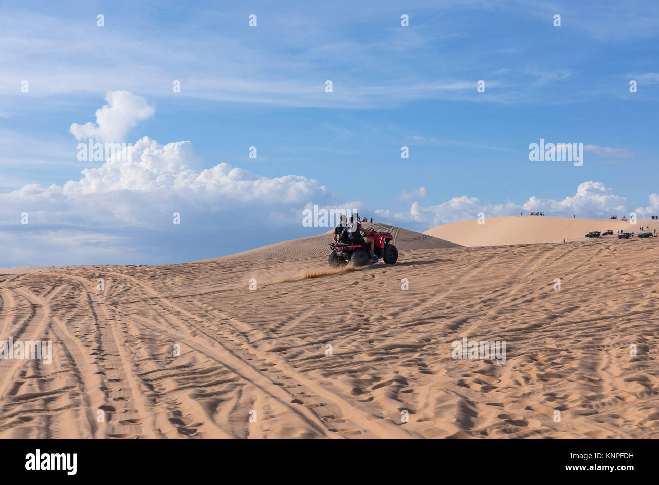 Dunes près de Mui Ne. Groupe de hors route au-dessus de dunes dans l'arrière-plan. Journée ensoleillée avec ciel bleu et nuages. Dunes de sable de Mui Ne au Vietnam , Banque D'Images