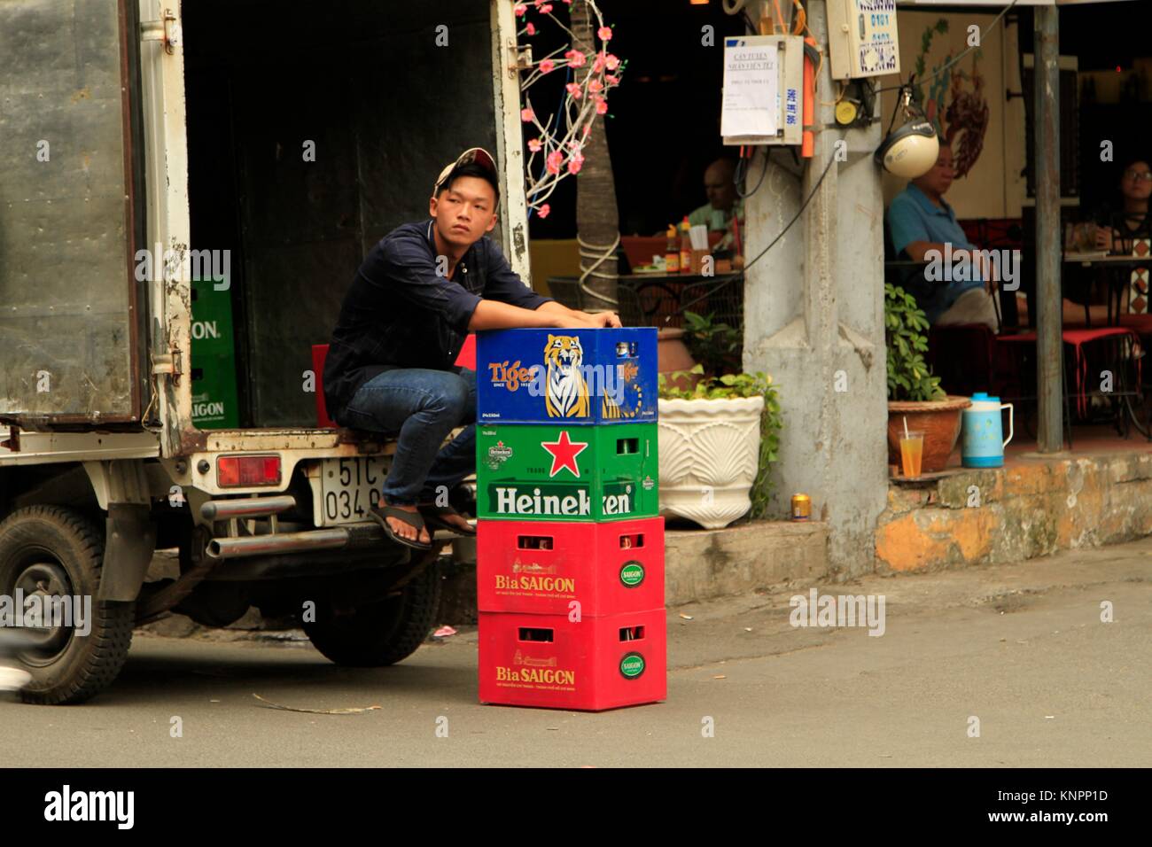 Homme assis à l'arrière d'un camion de livraison de bière à Ho Chi Minh Ville, Vietnam Banque D'Images