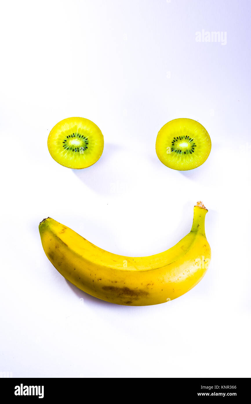 Tranches de Kiwi vert banane jaune symbole de smiley Fruits frais isolé sur fond blanc Banque D'Images