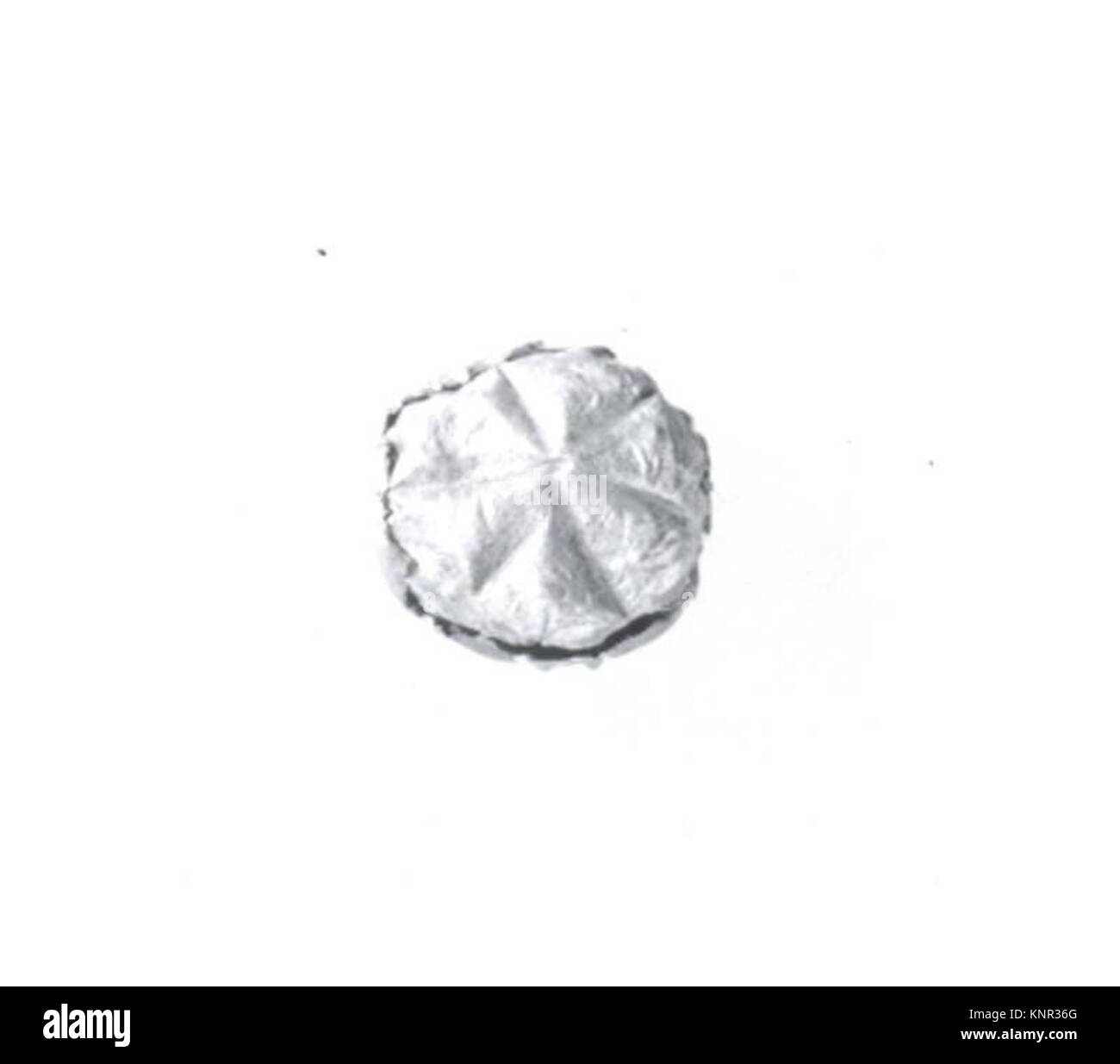 Ce bouton est une petite attache ancienne en métal ou en céramique, utilisée pour sécuriser les vêtements ou les textiles. Banque D'Images