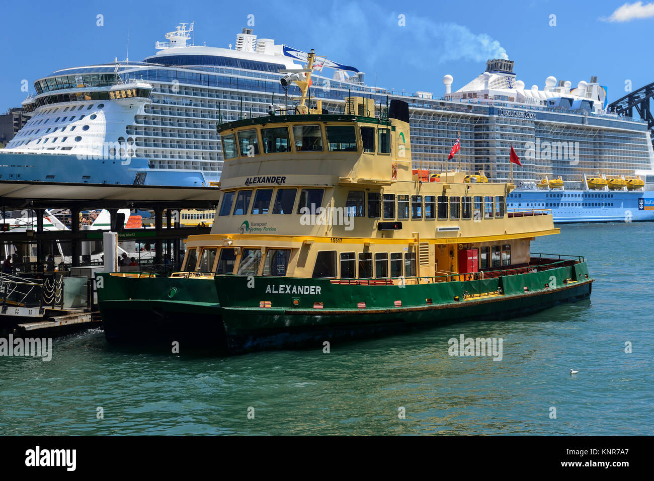 Bateau arrivant à Circular Quay, avec bateau de croisière amarré au terminal passagers d'outre-mer en arrière-plan - Sydney, New South Wales, Australia Banque D'Images