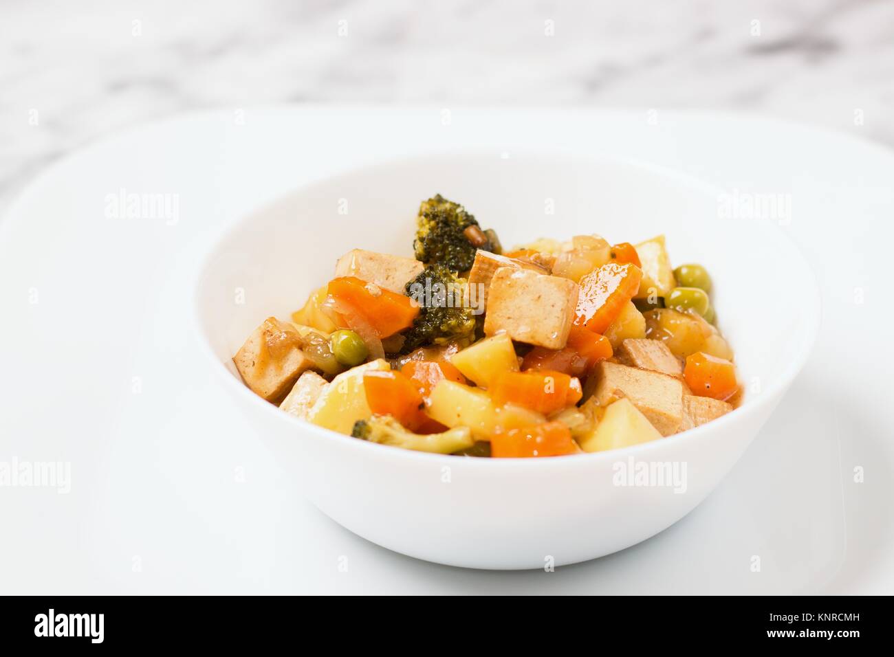 Bol blanc de style asiatique de repas vegan tofu fumé et légumes cuits Banque D'Images