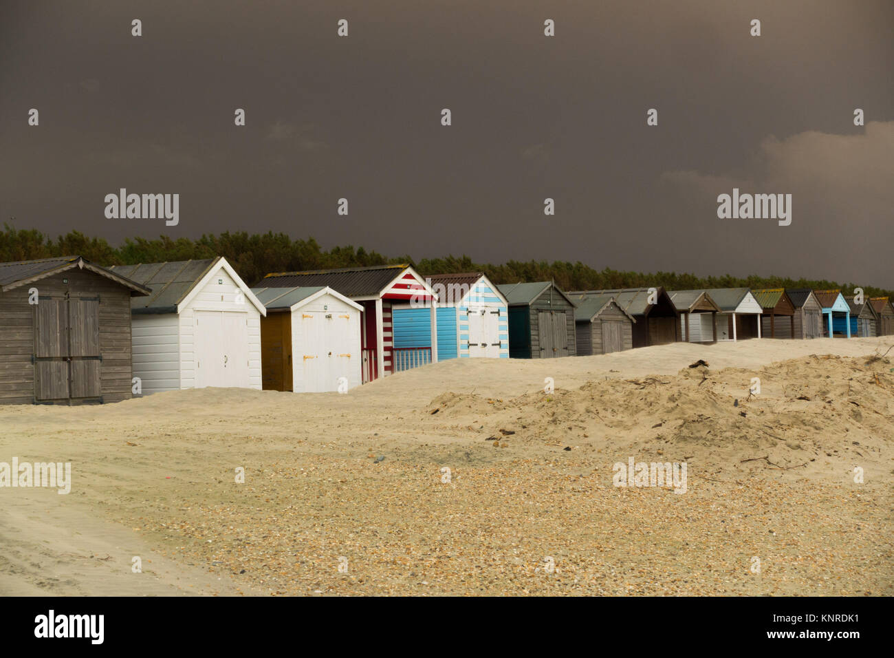 Cabines de plage à West Wittering Beach menacés en empiétant sand Banque D'Images