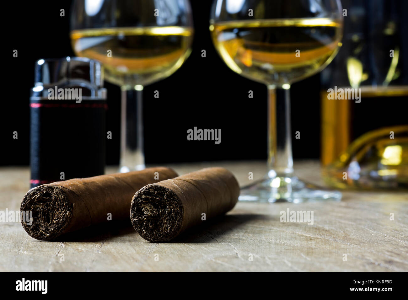Cigares cubains, bouteille et deux verre de whisky et plus léger, sur la vieille planche de bois, avec l'arrière-plan flou Banque D'Images