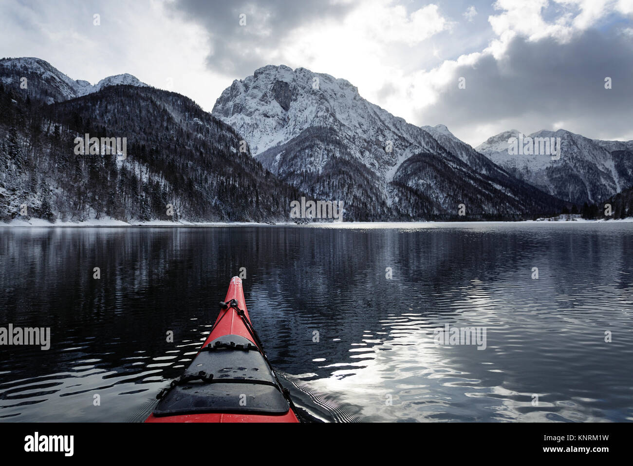 Pointe du kayak rouge dans des conditions hivernales sur une froide journée d'hiver au lac de Predil, Alpes, Italie. Banque D'Images