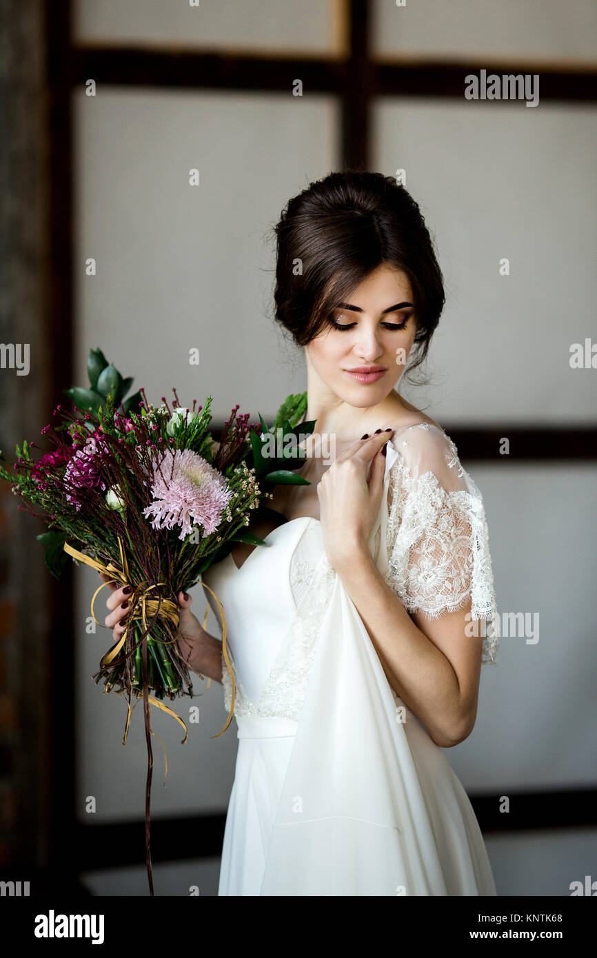 Belle robe de mariée assis sur une chaise à l'intérieur dans dark studio intérieur comme à la maison. Banque D'Images