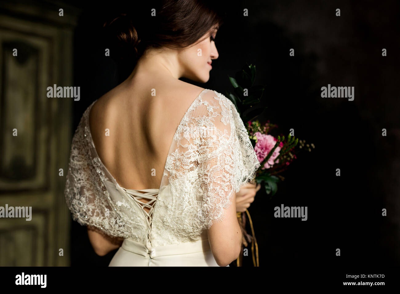 Belle robe de mariée assis sur une chaise à l'intérieur dans dark studio intérieur comme à la maison. Banque D'Images