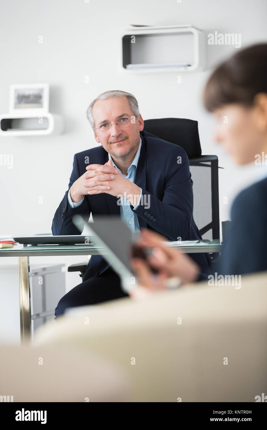 Senior businessman with hands clasped in meeting room at office Banque D'Images