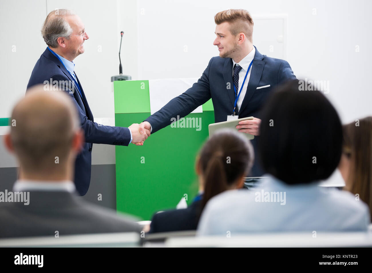 Certains hommes se serrer la main avec collègue in lecture hall Banque D'Images