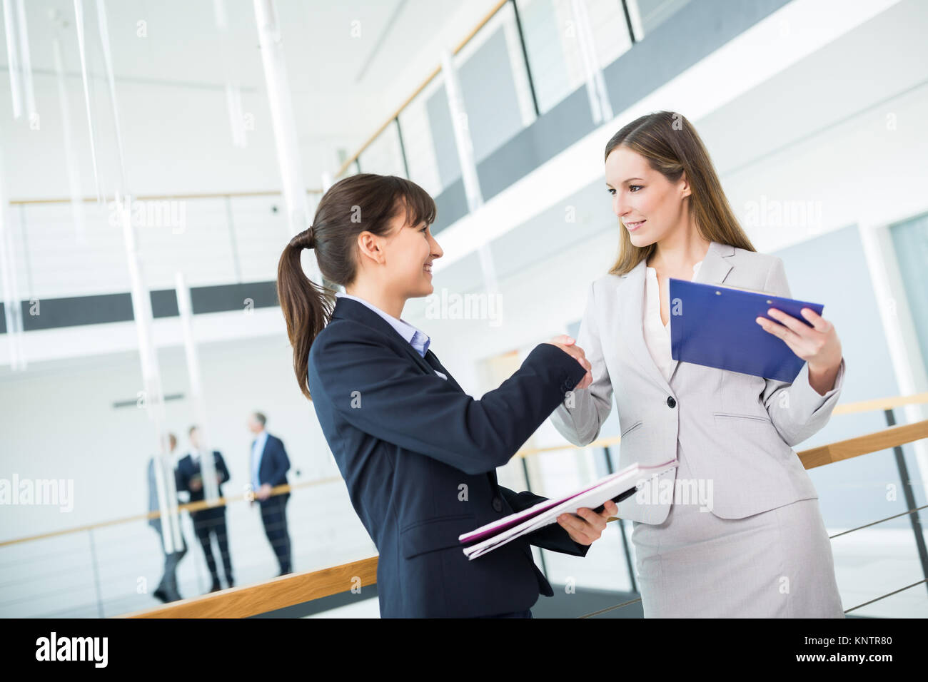 Confident female professional shaking hands with collègue alors que standing in office Banque D'Images
