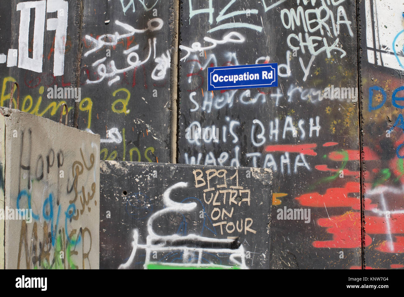 Plaque de rue à l'occupation Road entouré par un graffiti sur le mur de séparation en Cisjordanie, Bethléem, Palestine Banque D'Images