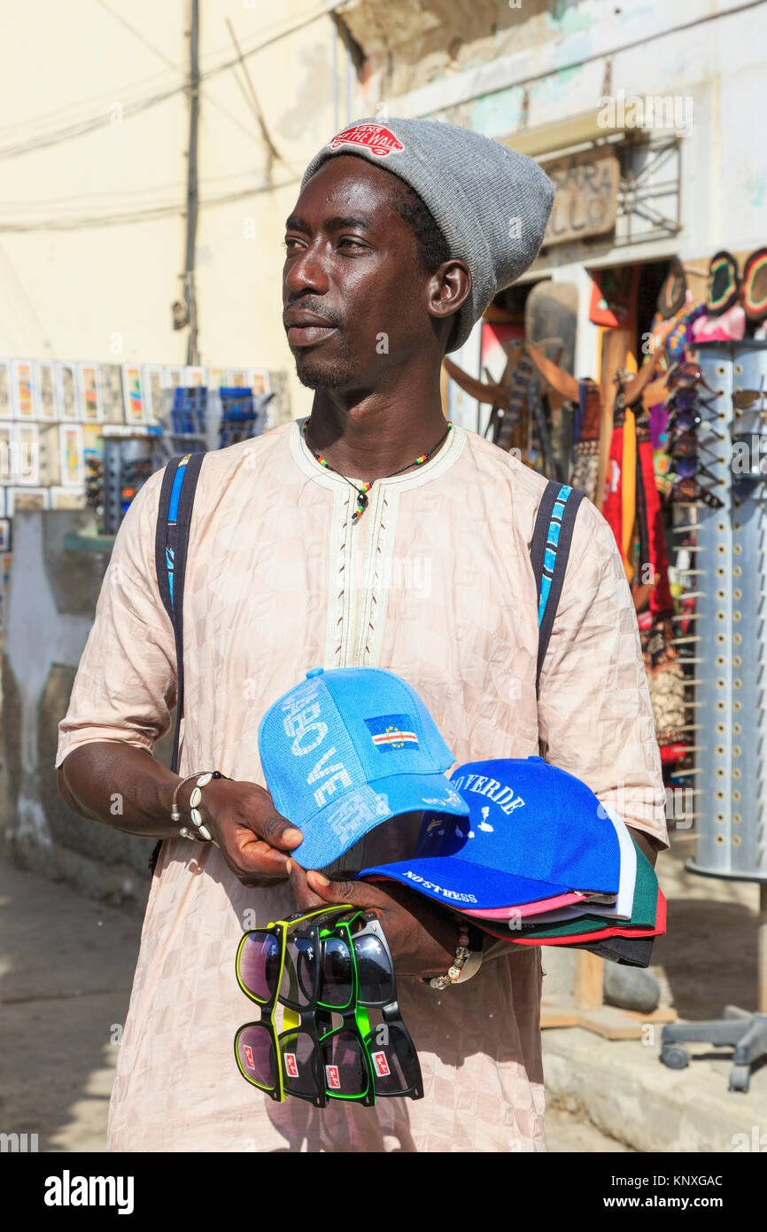 L'homme du Sénégal vente de chapeaux de base-ball avec le Cap Vert gaufré  logo et de fausses Ray Ban lunettes de soleil à la zone touristique de  Santa Maria, Sal, Salina Photo