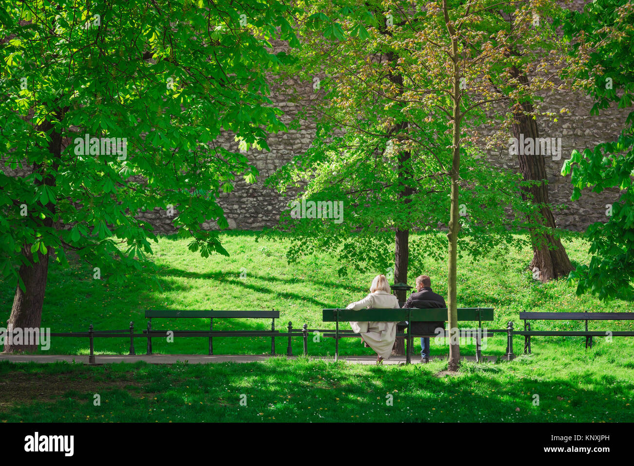 Couple banc de parc Europe, sur un après-midi à la fin du printemps un couple se détendre sur un banc dans le Parc Planty, Cracovie, Pologne. Banque D'Images