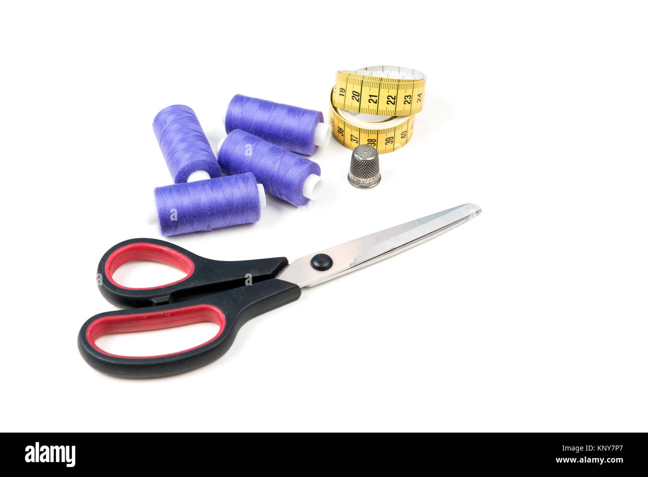 Outils et fournitures de couture, fils à coudre violet moyen, jaune ruban à  mesurer avec des chiffres noirs, gros ciseaux et virole métallique sur fond  blanc backgroun Photo Stock - Alamy