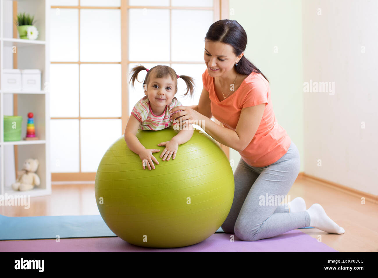 Mère avec childdoing exercices avec ballon de gymnastique à la maison. Concept de prendre soin de la santé du bébé. Banque D'Images