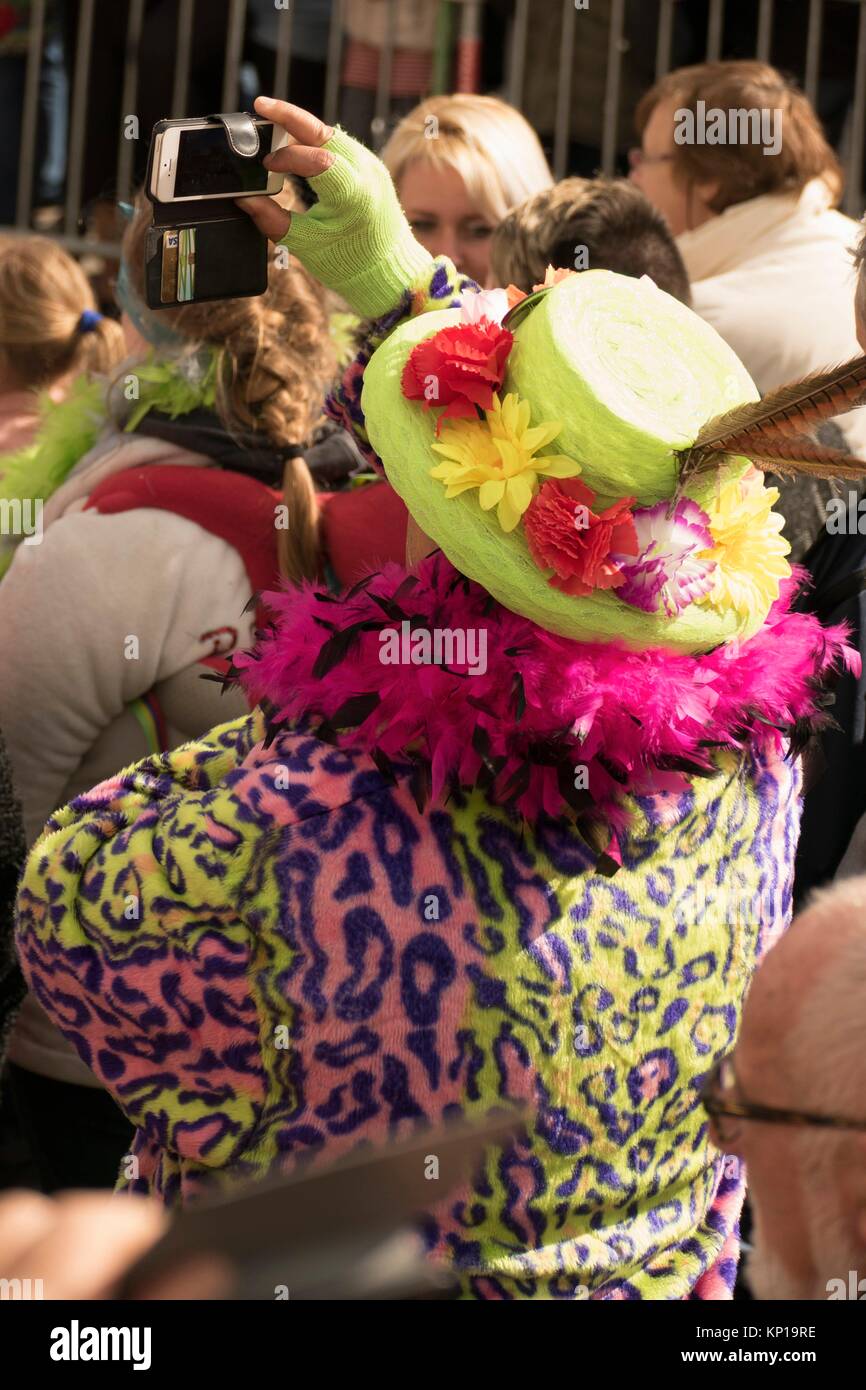 Carnival reveler en vert staw hat, magenta boa et léopard photographier la parade de Pâques à Cassel, France. Banque D'Images