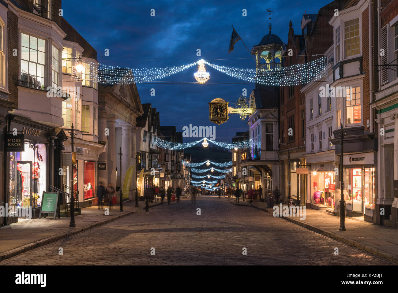 La grande rue à Guildford avec des lumières de Noël et la célèbre Guildhall gold réveil en bleu l'heure sur un jour de shopping de fin de soirée, en Angleterre, Royaume-Uni Banque D'Images
