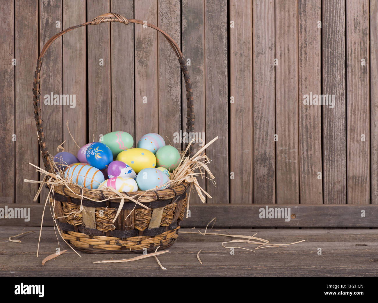 Les oeufs de Pâques colorés dans un panier sur une surface en bois Banque D'Images