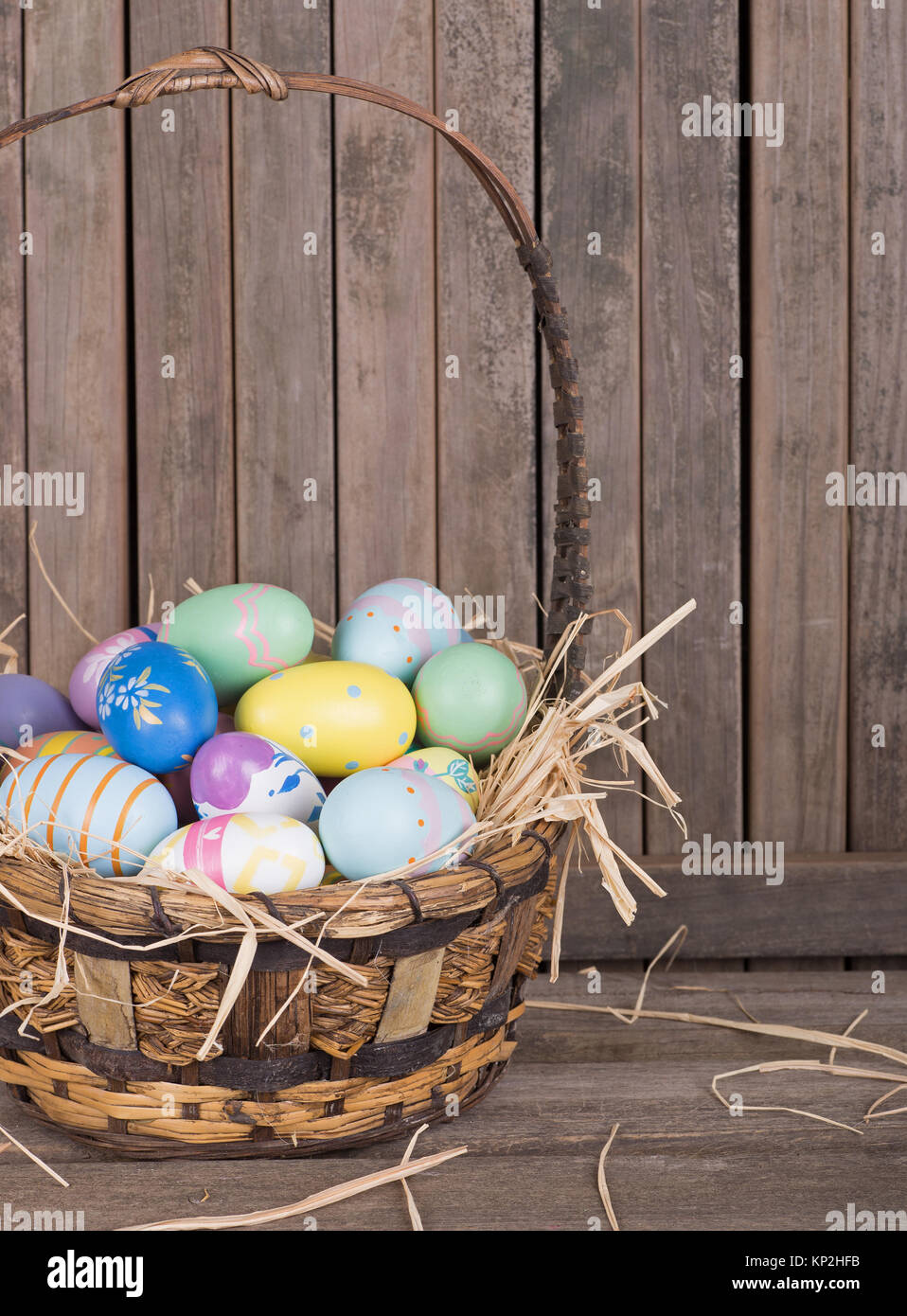 Les oeufs de Pâques colorés dans un panier sur une surface en bois Banque D'Images