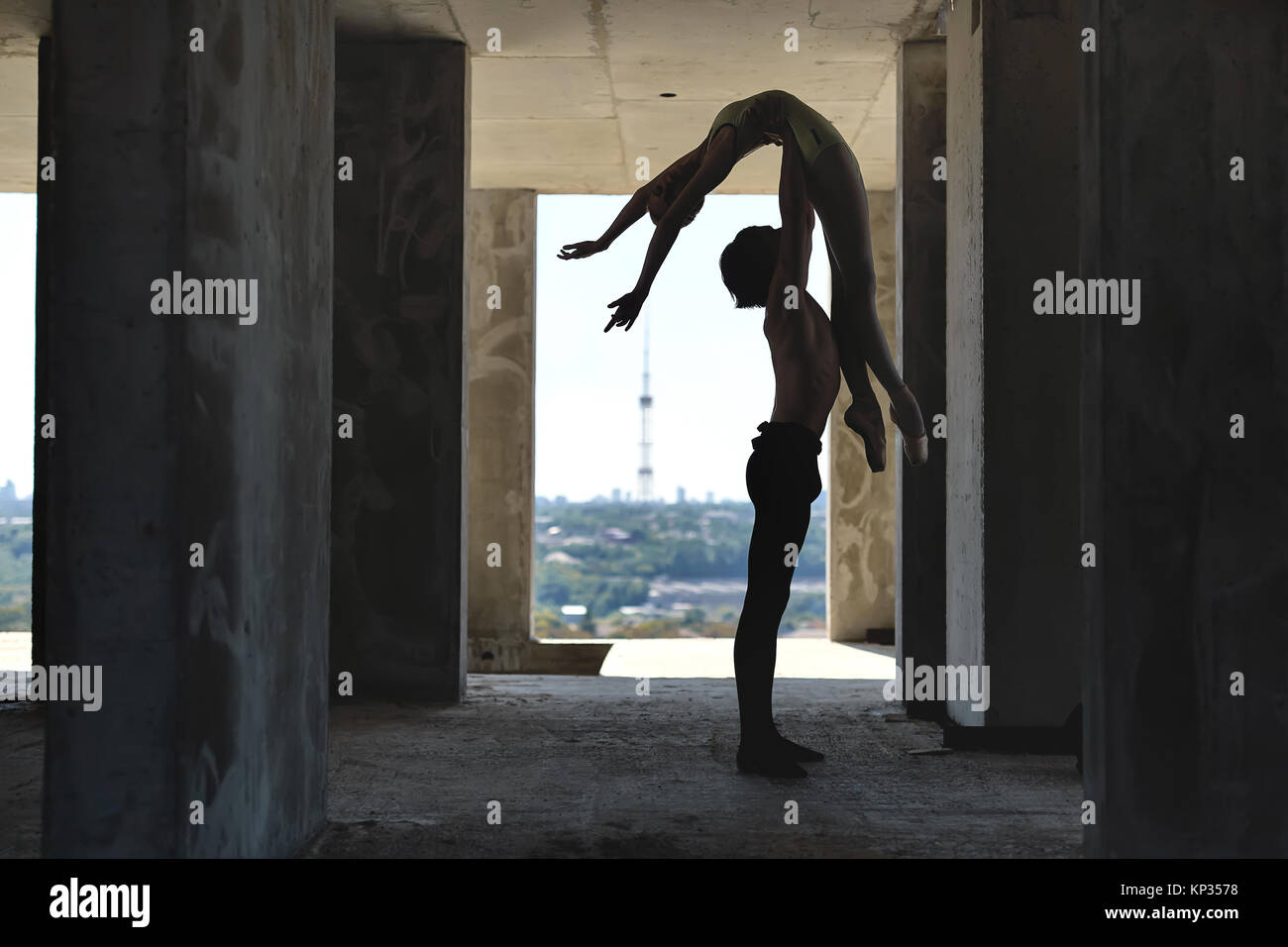 Silhouette de couple de danseurs de ballet qui posant sur le sol en béton de l'édifice inachevé sur le paysage urbain historique. Guy est titulaire d'une fille en th Banque D'Images
