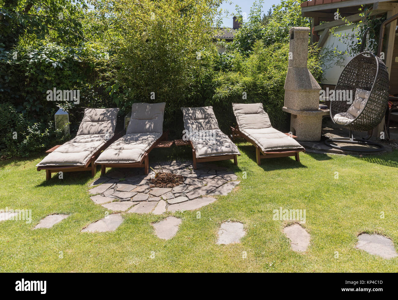 Chaises de jardin sur l'herbe verte, le Bamboo fence arrière-plan. Lit de jardin pour bronzer et se reposer. Quatre lit de jardin. Banque D'Images