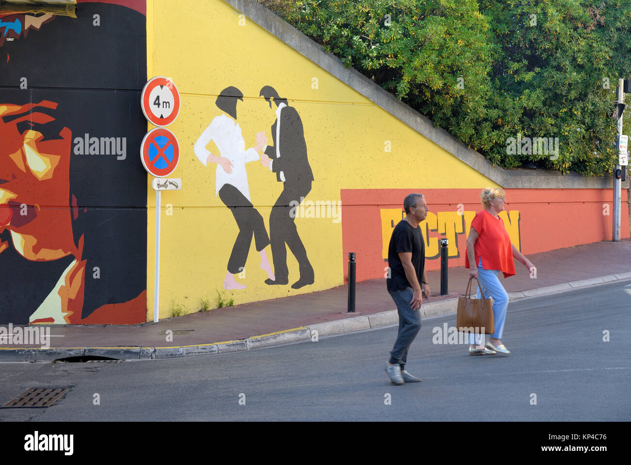 Un couple marche passé Street Art basé sur le film 'Pulp Fiction', près du Boulevard de la Croisette Cannes Côte d'Azur France Banque D'Images