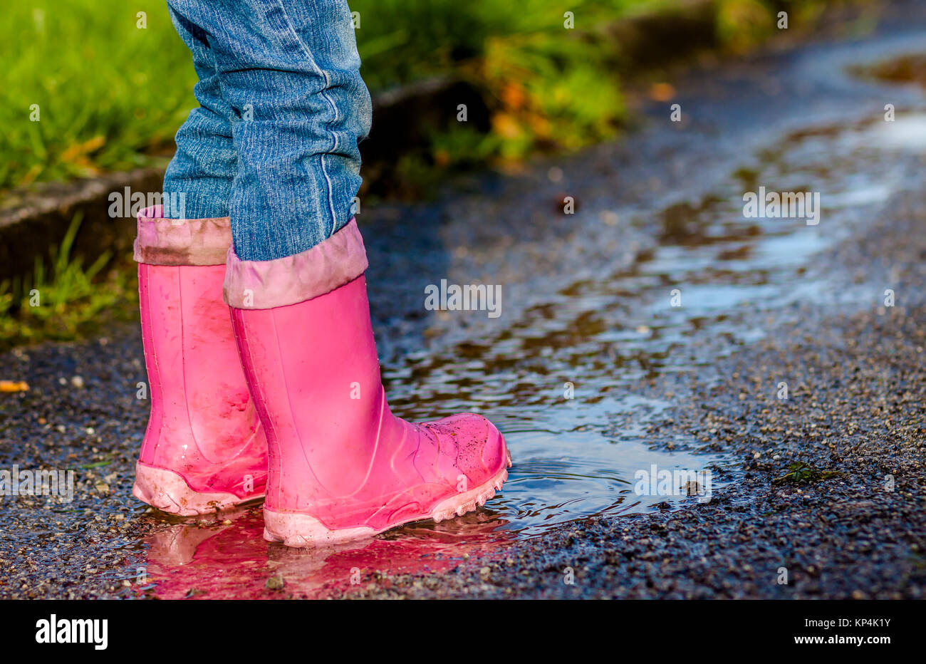 Little girl with pink wellys dans la flaque sur la rue Banque D'Images