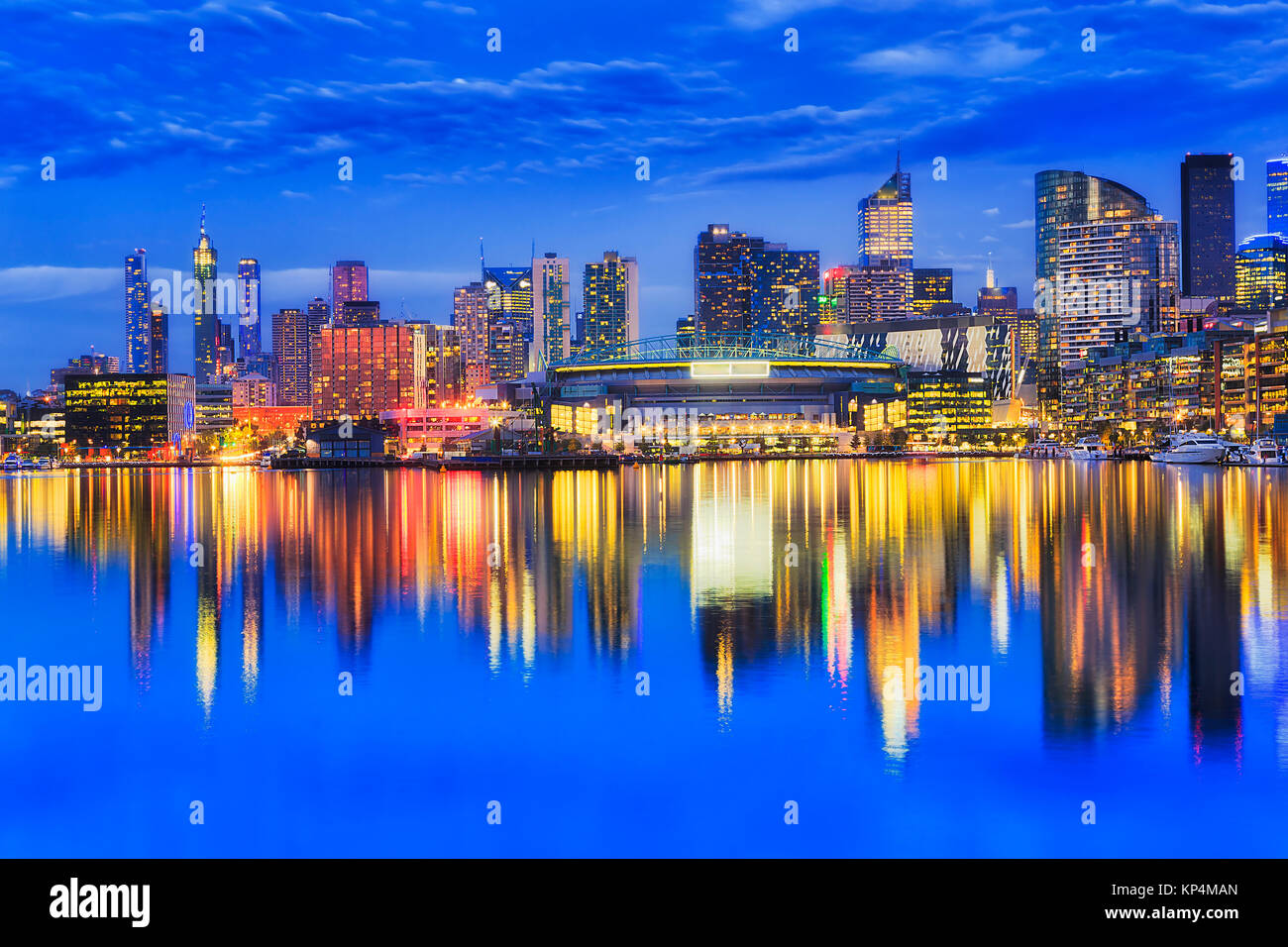 Iilluminated urbain lumineux au bord de l'architecture de banlieue de Melbourne Docklands se reflétant dans les eaux de la rivière Yarra encore au coucher du soleil. Banque D'Images