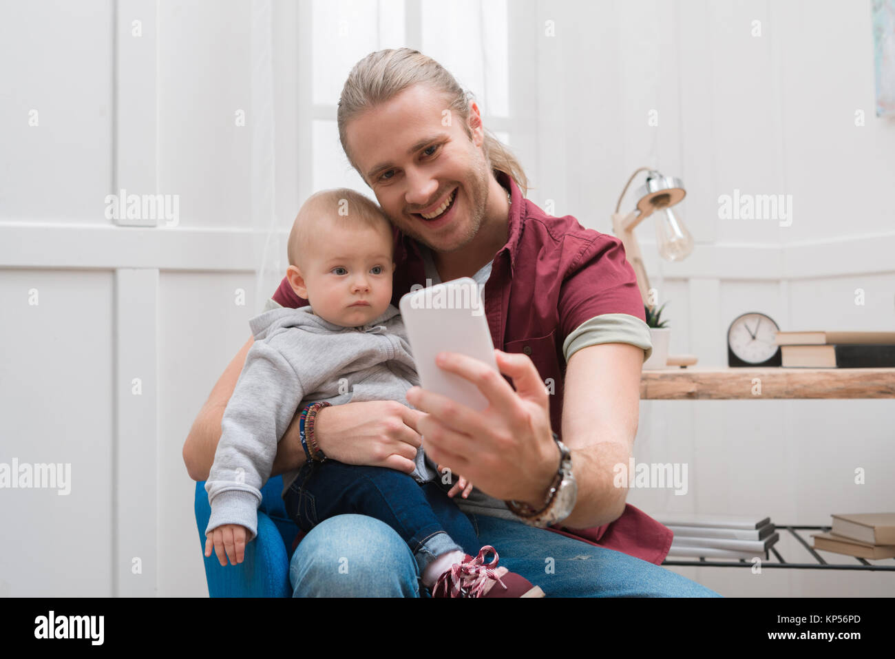 Père souriant en tenant avec selfies fils à la maison Banque D'Images