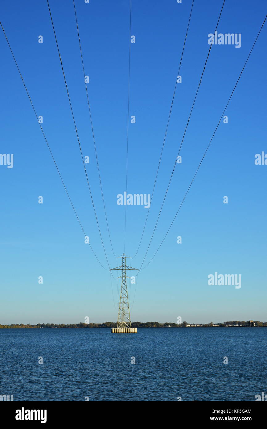 La tour de transmission de puissance dans un lac isolé contre un ciel bleu Banque D'Images