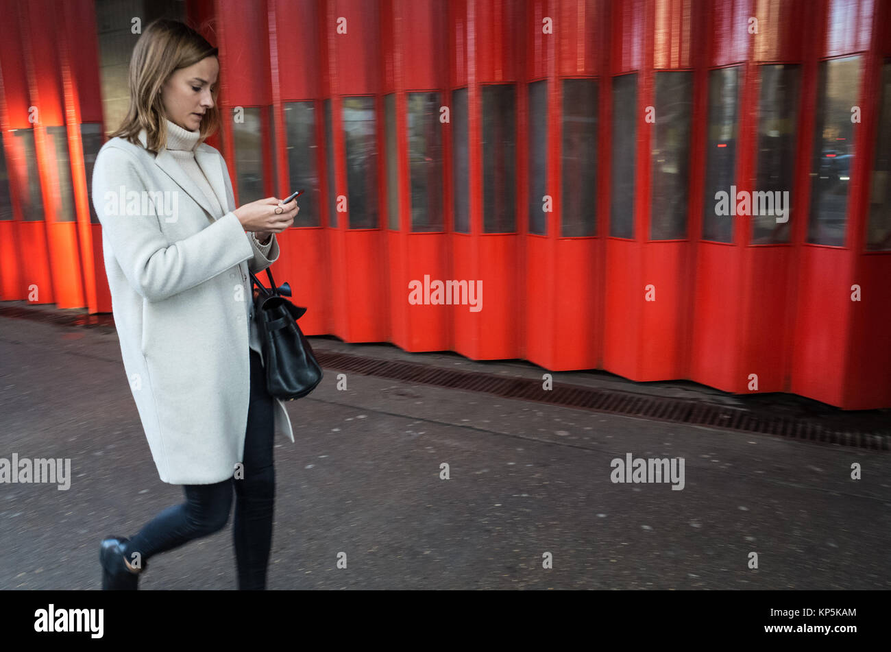 Une femme de race blanche sur son téléphone portable en marchant dans la rue Banque D'Images