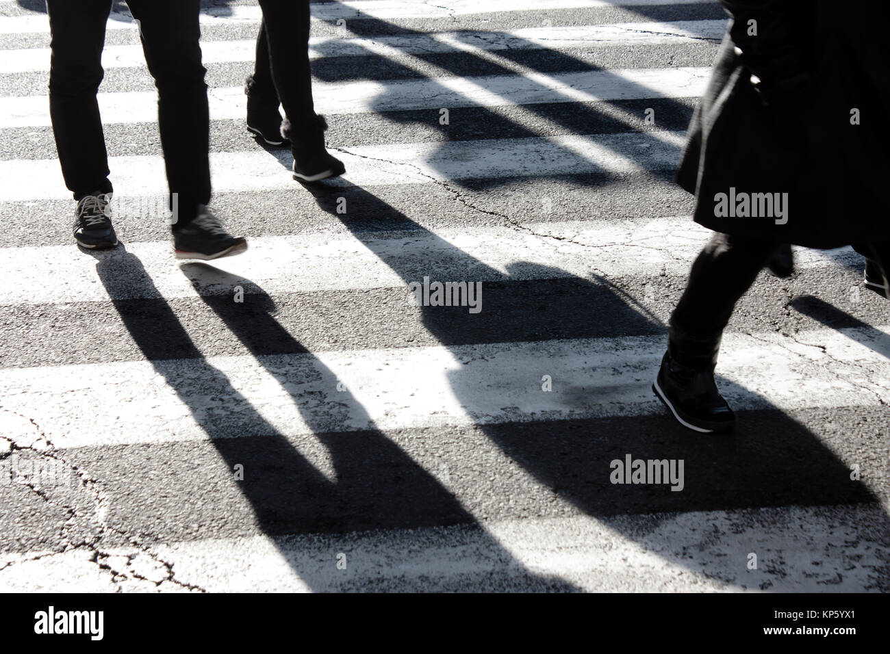 Ombres et des silhouettes de personnes traversant la rue de ville en hiver en noir et blanc Banque D'Images