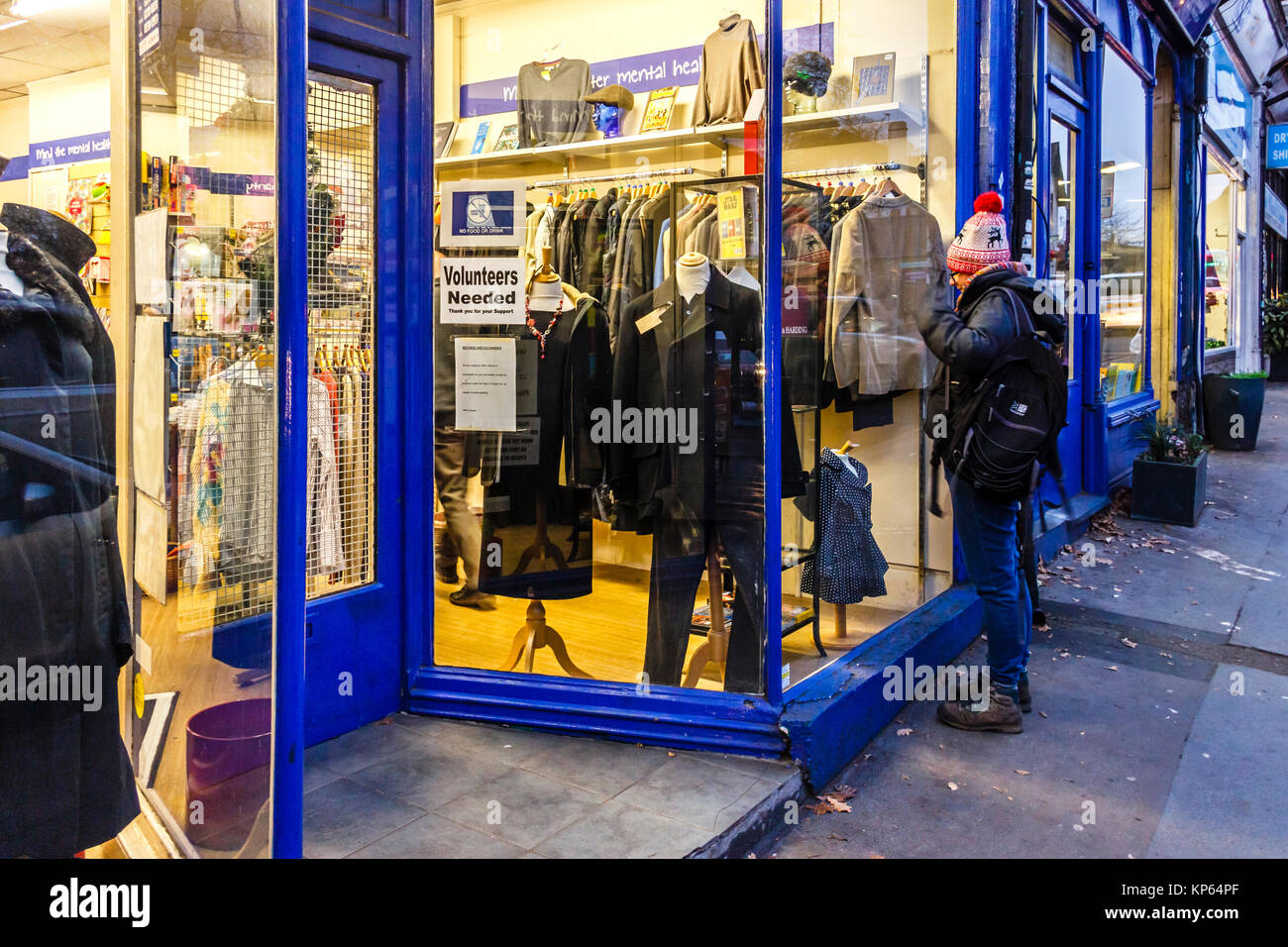 Femme de navigation dans la fenêtre d'un magasin de charité à Highgate, Londres, UK Banque D'Images