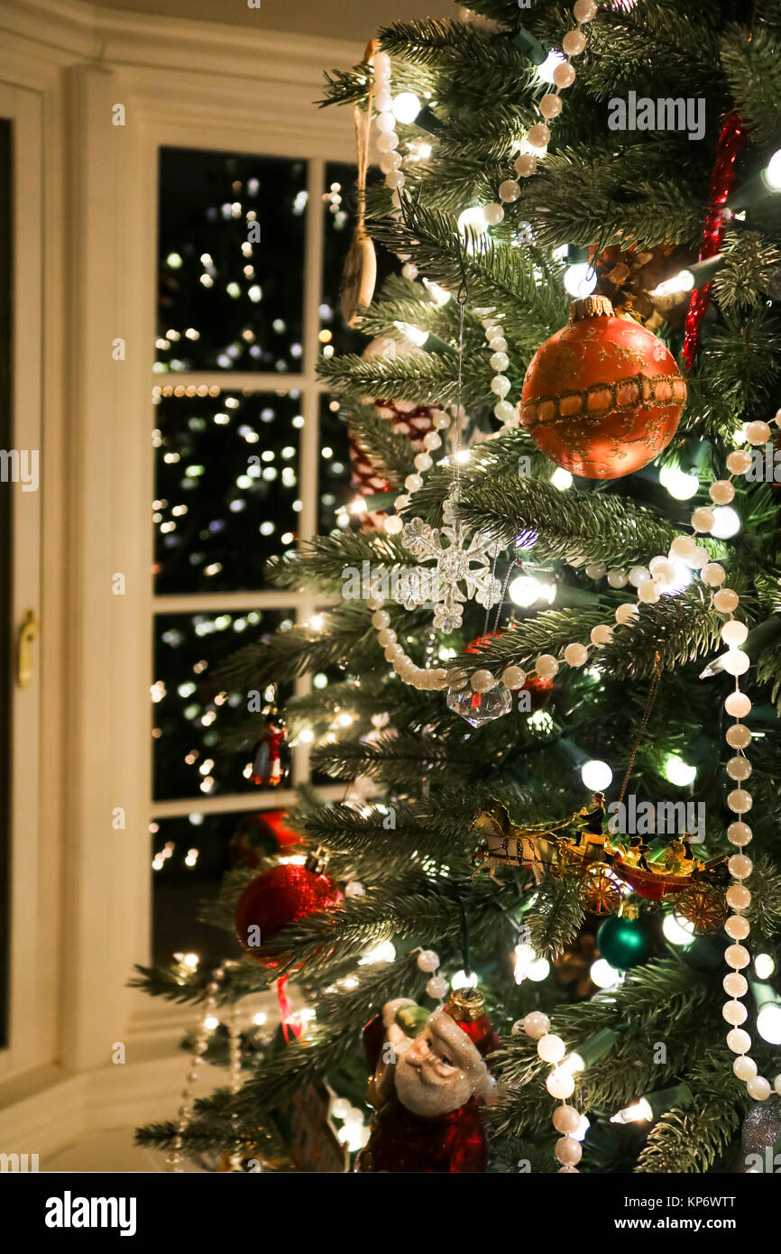 Branches de l'arbre de Noël à l'ancienne avec des perles et un assortiment de beaux ornements reflètent dans fenêtre en baie Banque D'Images