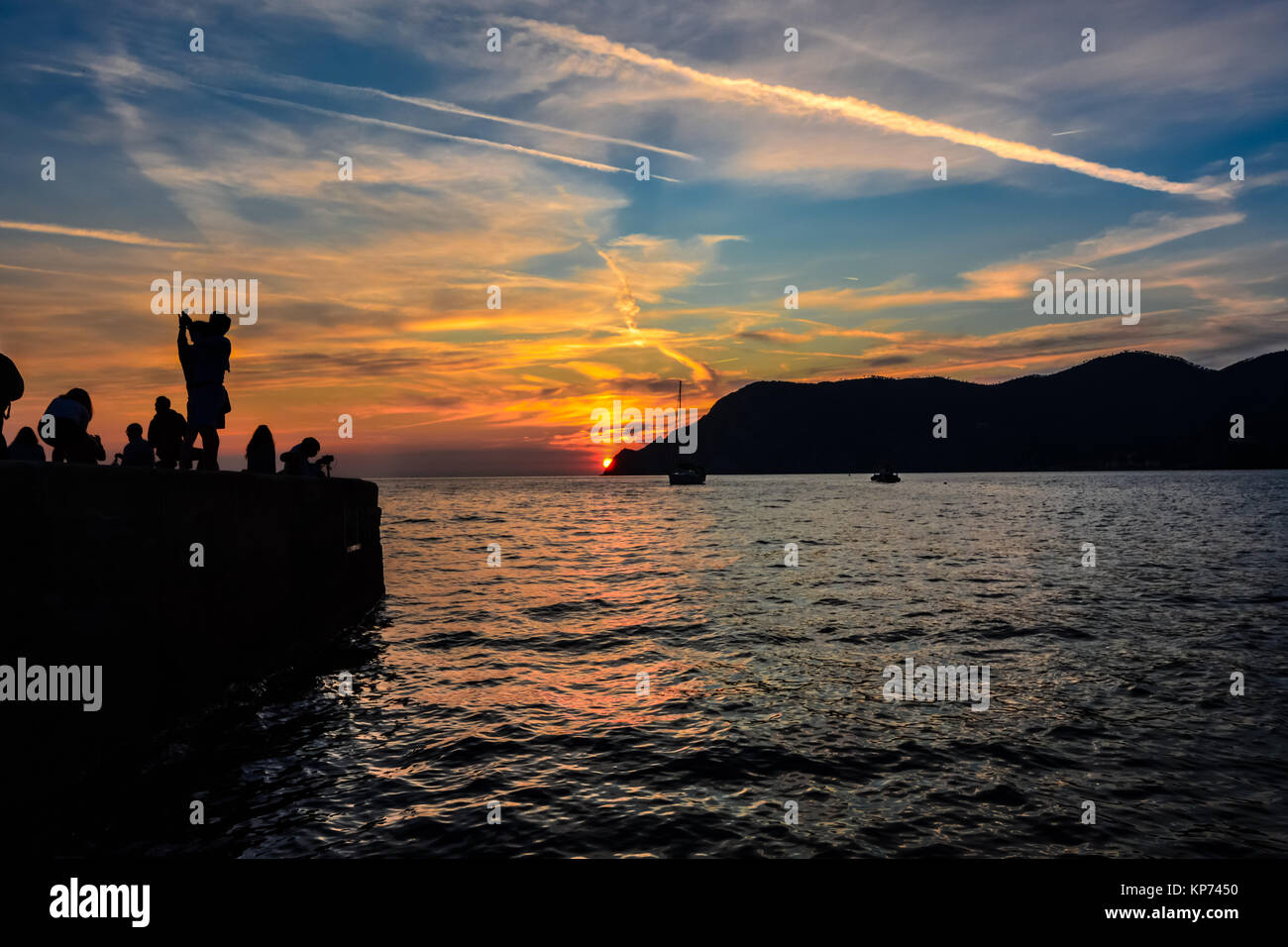 Un couple danse en silhouette sur le quai de Vernazza, Cinque Terre Italie en face d'un merveilleux coucher de soleil et de bateaux dans la mer Banque D'Images