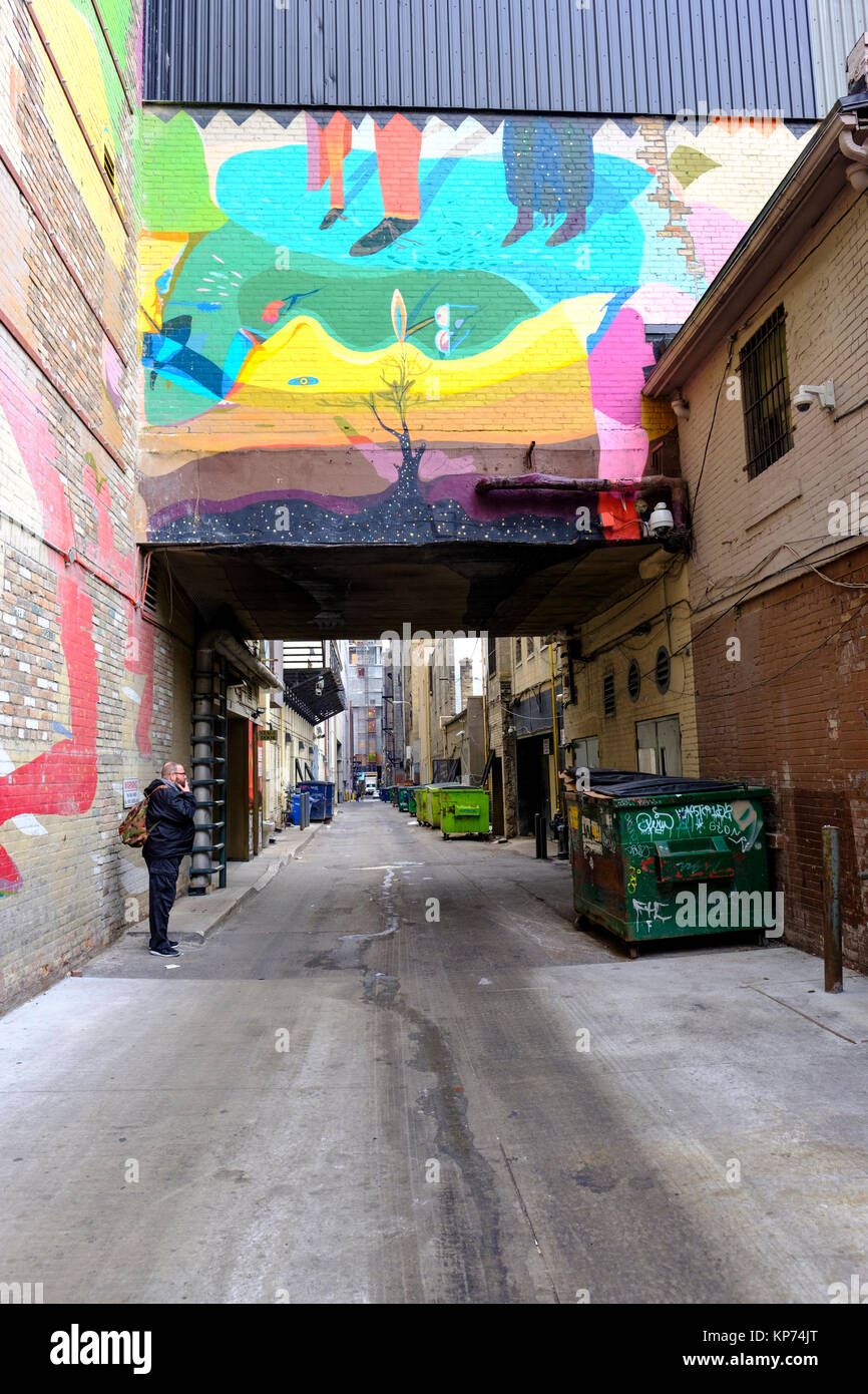 O'Keefe ruelle Lane avec de nombreux espaces verts les bennes alignés contre le mur, l'homme qui fume, graffiti art, centre-ville de Toronto, Ontario, Canada. Banque D'Images