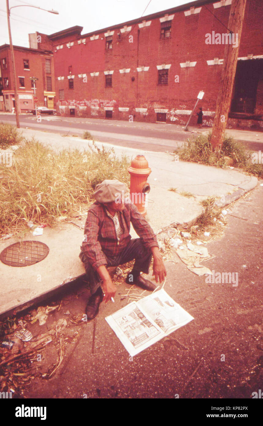 Homme tuer le temps dans le nord de Philadelphie, Août 1973 Séance sur route trottoir Banque D'Images